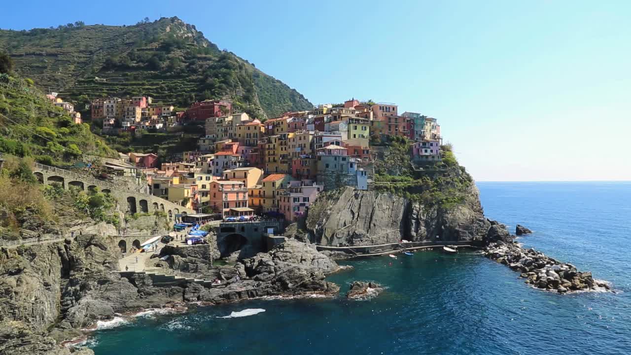 vista statica con vista sulla costa di manarola, sul porto e sulla baia con colorate case di città e acqua limpida in una soleggiata giornata estiva nelle cinque terre, liguria italia