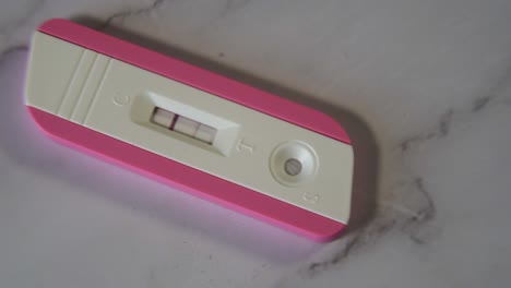 primer plano de una prueba de embarazo rosa positiva en la mesa de mármol en 4k