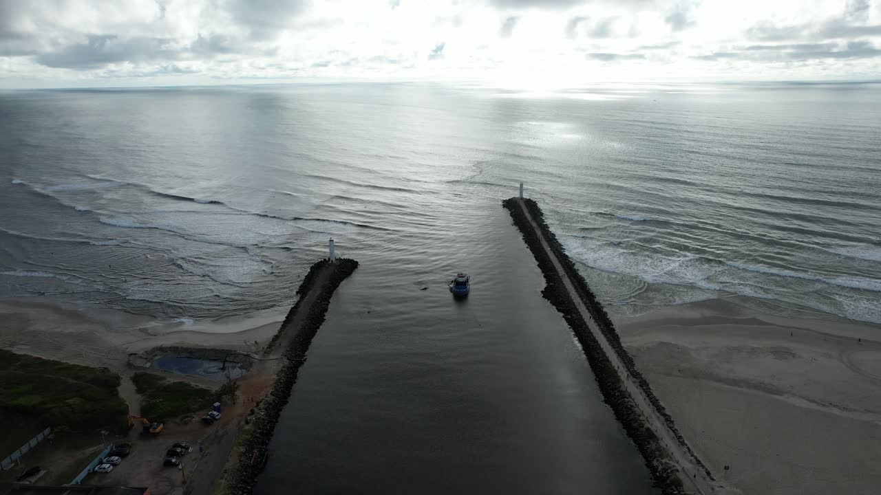 drone shot moving forward entering the sea through a channel, cloudy dawn