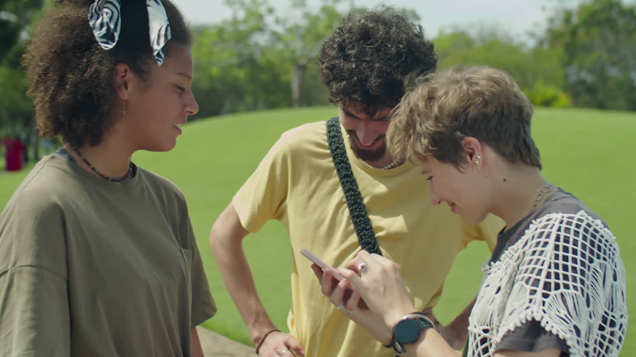 Young Friends Using Smartphone and Chatting in Park