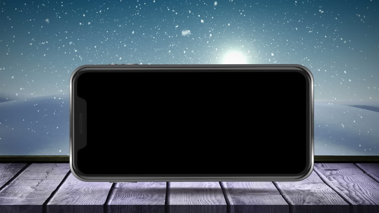 animación digital de un teléfono inteligente en superficie de madera contra la nieve que cae sobre el paisaje de invierno