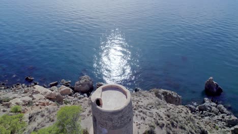 Dolly-in-aerial-view-of-medieval-ruins-next-to-the-stunning-blue-sea-and-cliffs