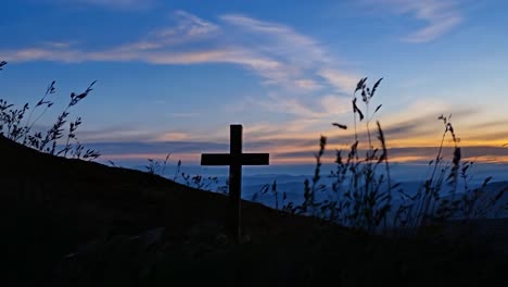 wooden cross is silhouetted against a beautiful sunset sky with clouds moving in the background