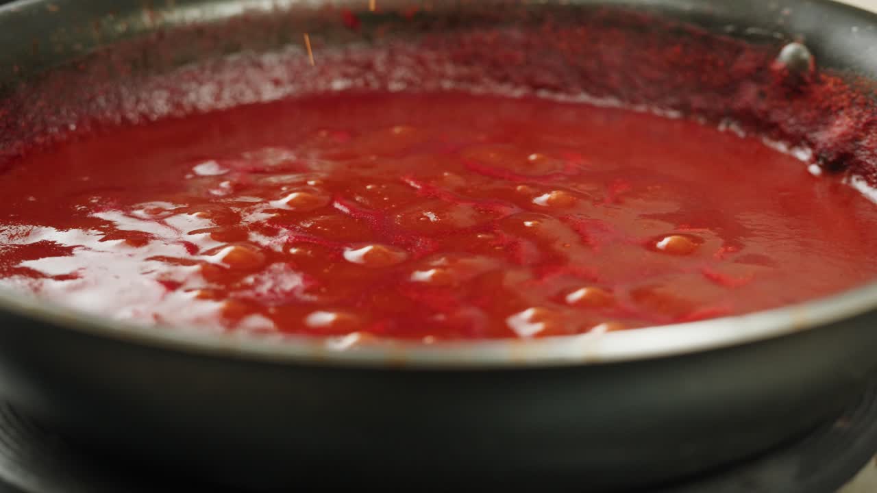 Boiling tomato sauce on a frying pan close-up. Cooking tomato sauce or soup. Traditional Italian Mexican Asian dish. High quality studio shot for cafe, restaurant close up. Marinara sauce for Italian pasta