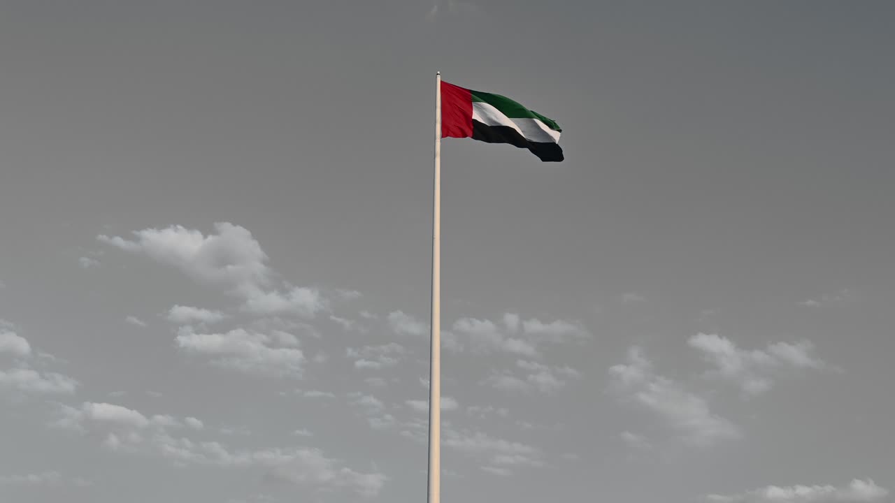 efecto de salpicadura de color: bandera de los emiratos árabes unidos ondeando en el aire cielo azul nublado en el fondo, efecto de color aislado, día nacional de los emiratos árabes unidos, video de 4k