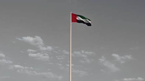 Farbspritzeffekt:-Flagge-Der-Vereinigten-Arabischen-Emirate-Weht-In-Der-Luft,-Bewölkter-Blauer-Himmel-Im-Hintergrund,-Isolierter-Farbeffekt,-Nationalfeiertag-Der-Vereinigten-Arabischen-Emirate,-4k-Video