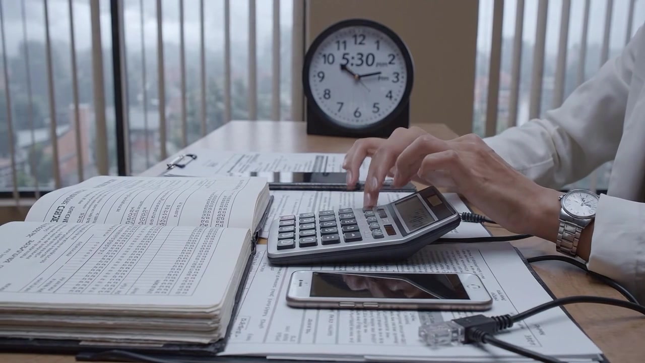 Un ambiente professionale: calcolo delle finanze con precisione a una scrivania circondata da documenti, una calcolatrice e tecnologia in un ambiente ben organizzato