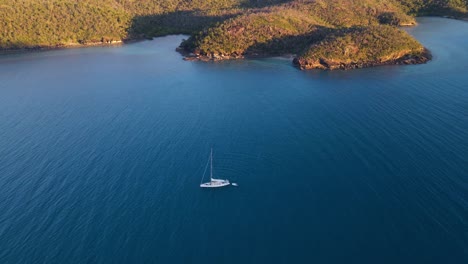 sailboat with dinghy floating on calm water of nara inlet - hook island in whitsundays, australia