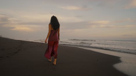 Young-Woman-In-Red-Dress-Walking-Alone-In-A-Tropical-Sandy-Seacoast