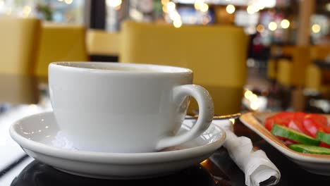 una taza de café blanca en una mesa en una cafetería