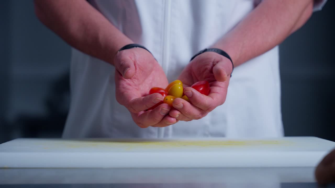 un chef colocando tomates en una tabla de cortar en la cocina