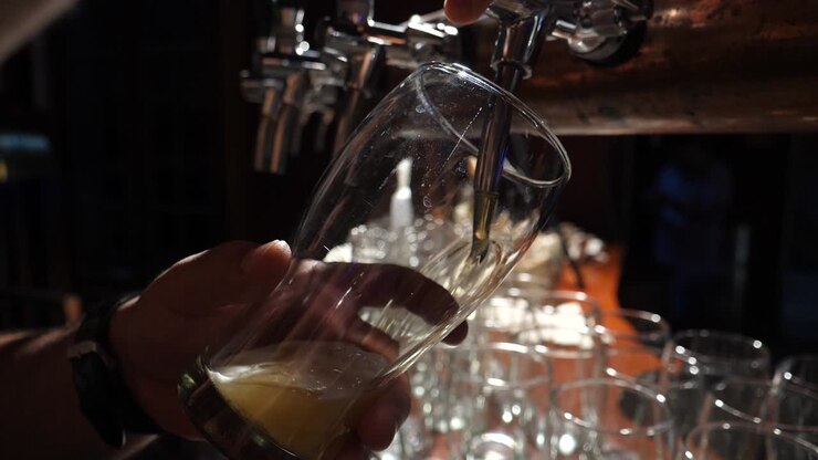 Primo piano di birra dorata che viene versata dalla spina in un bicchiere.