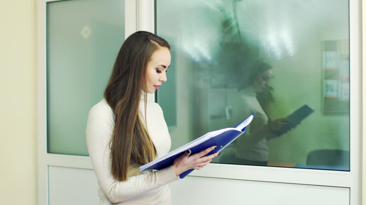 young woman with a folder for documents in the hands. portrait of a girl in the office