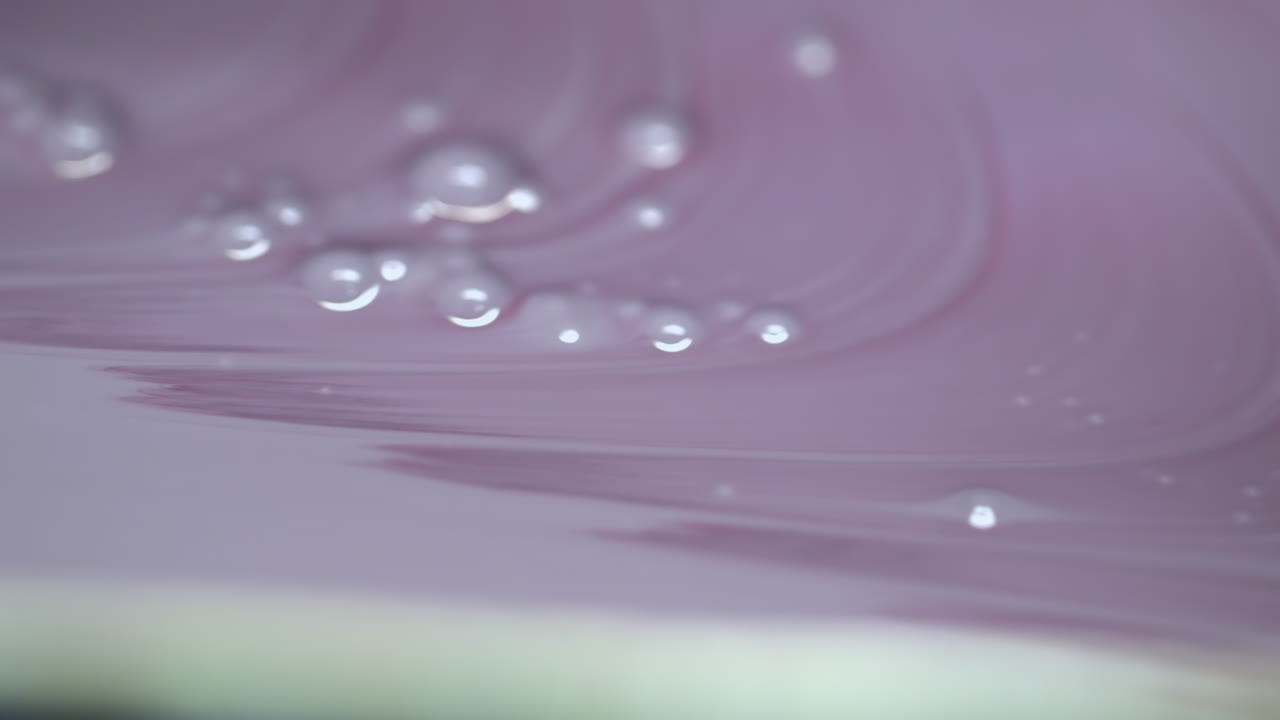 Extreme closeup of pale violet and green paint flowing endlessly in an abstract pattern