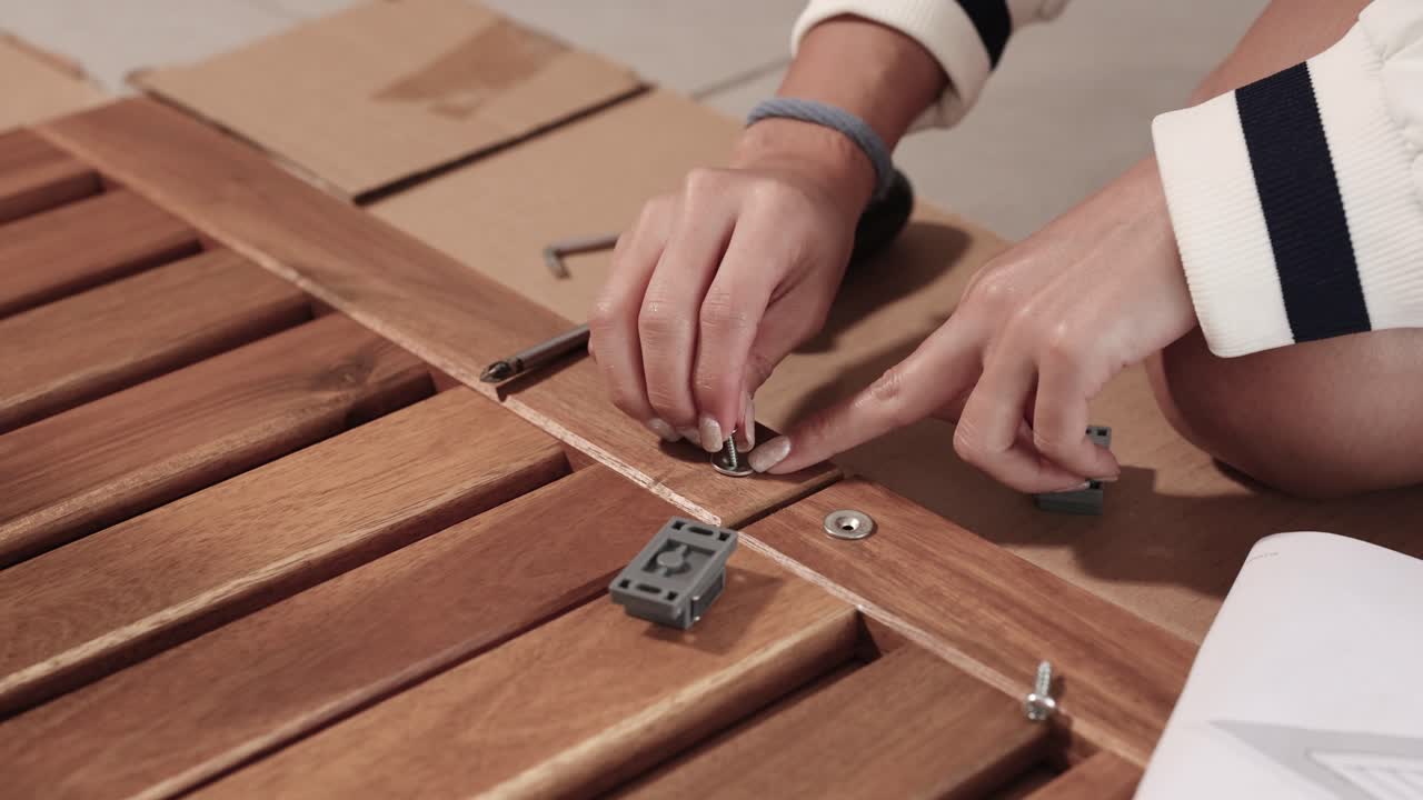 Hands assembling wooden furniture with tools in a well-lit indoor setting, focusing on precision and craftsmanship