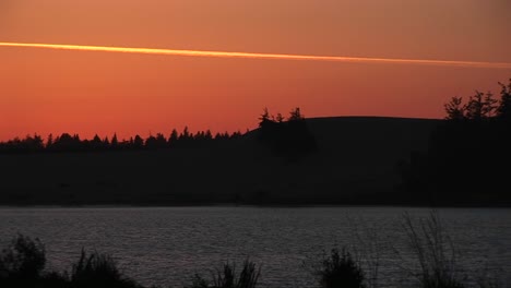 Spectacular-Footage-Of-A-Lake-And-Surrounding-Scenery-Under-An-Orange-Goldenhour-Sky