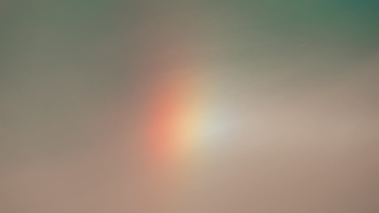 A subtle, soft sky with a faint vertical rainbow or sundog, blending warm and cool tones