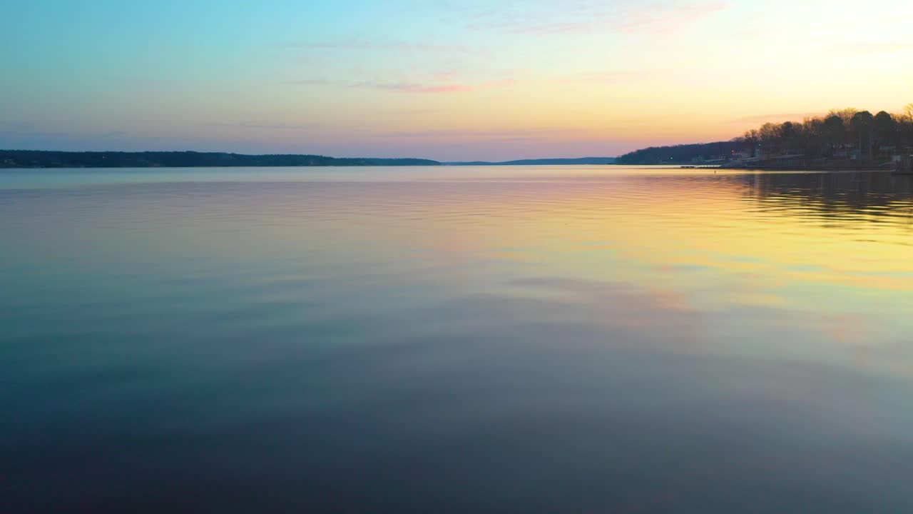vuelo bajo sobre el agua serena del gran lago o' los cherokees durante el reflejo del atardecer en oklahoma