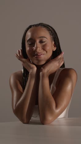 studio beauty shot of young woman with long braided hair sitting at table 5