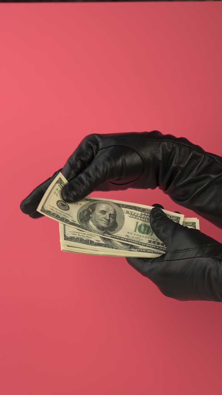Hands in Black Gloves Counting Hundred Dollar Bills on Pink Background
