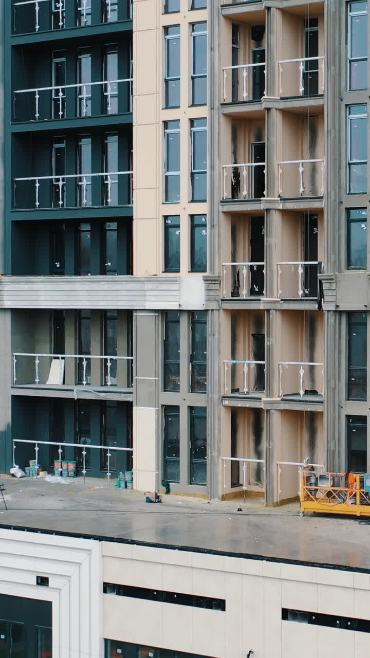 Tall apartment building. Construction of a multi-storey apartment building with windows and balconies. Camera rising up. Vertical video