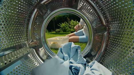 woman loading clothes into washing machine in garden