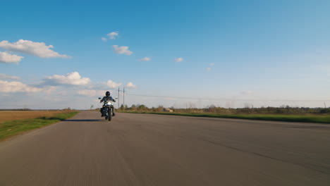 a lone biker riding on a deserted road wide angle