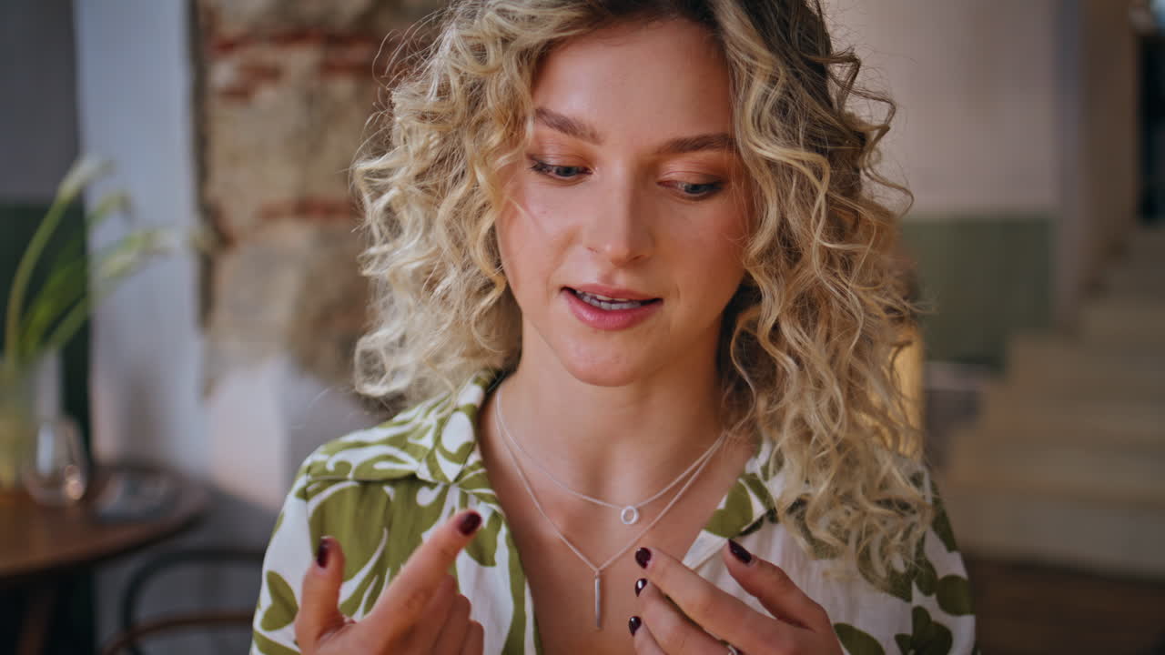 Positive girl telling story gesturing to unknown friends in restaurant closeup
