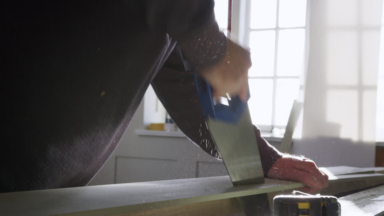 близкое изображение плотника, пилующего древесину в помещении