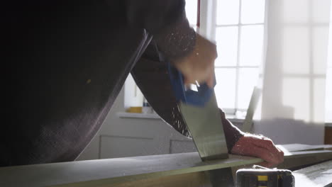 close up of carpenter sawing timber indoors