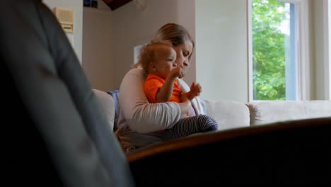 madre sosteniendo a su hijo sentado en el sofá 4k