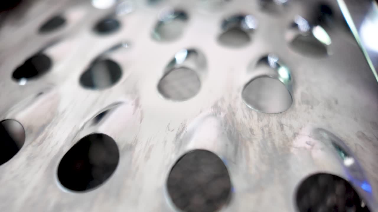 Close-up of silver cheese grater surface with oval holes