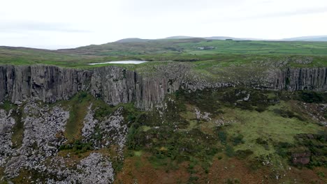 Aerial-panning-shot-of-majestic-cliffs-of-Fair-Head-cliffs-in-Northern-Ireland-overlooking-the-pristine-nature-and-unique-destination-for-an-adventure-for-hikers-and-climbers