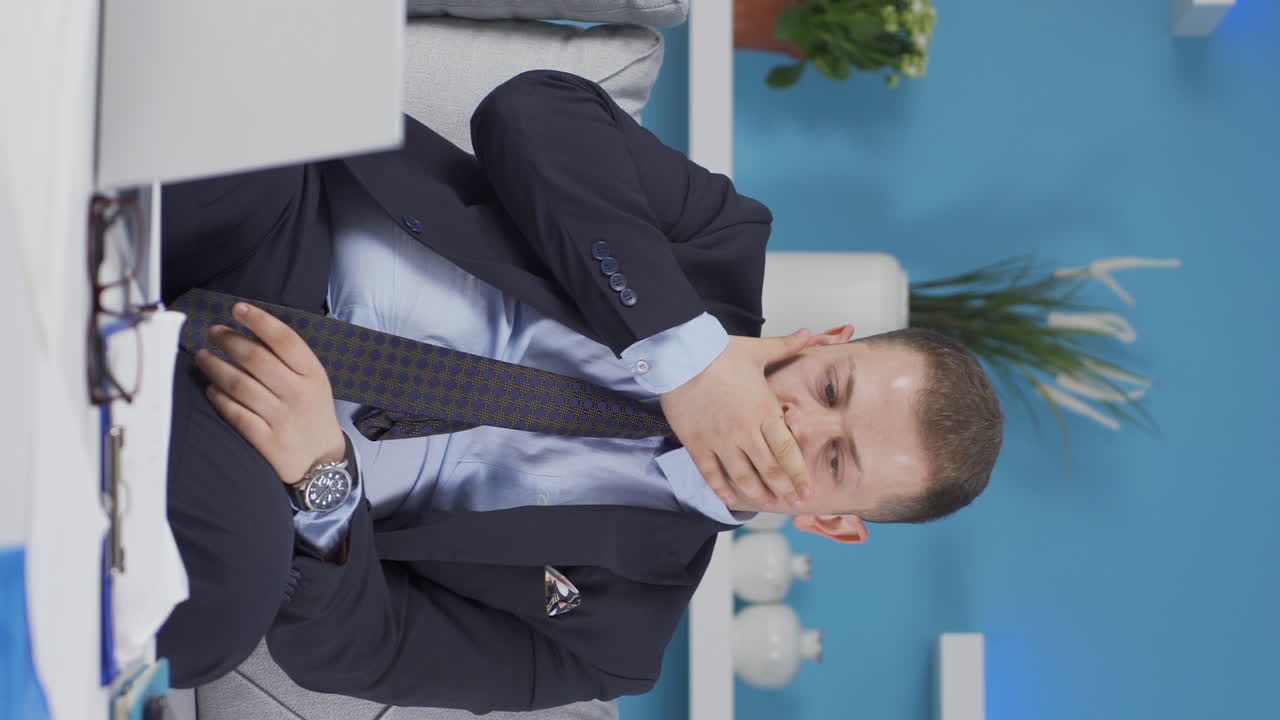 vídeo vertical de un trabajador de oficina en casa pensando deprimido y sintiéndose infeliz.