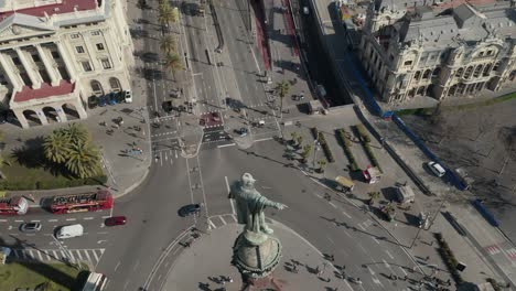 aerial: primer plano del monumento a colón en barcelona, españa en un hermoso día soleado con mucho tráfico de automóviles en la rotonda [4k]