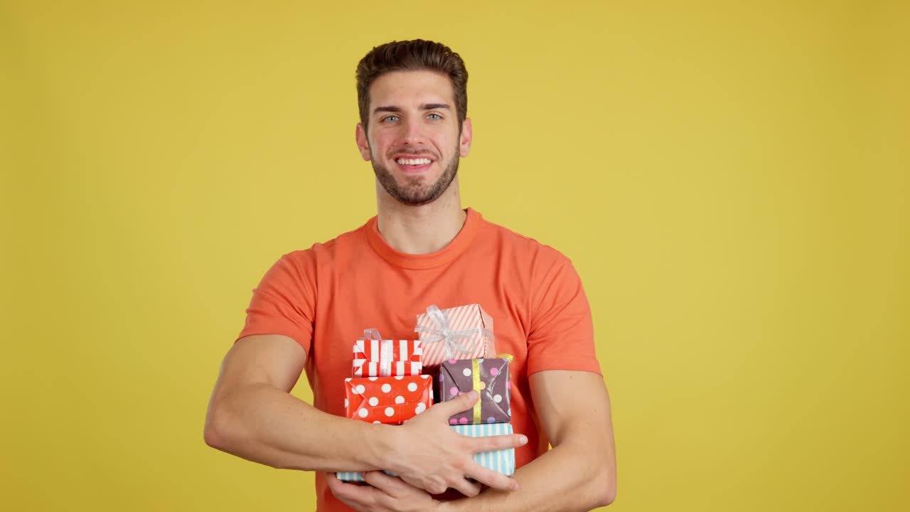 Happy Man Holding a Stack of Gifts on Yellow Background