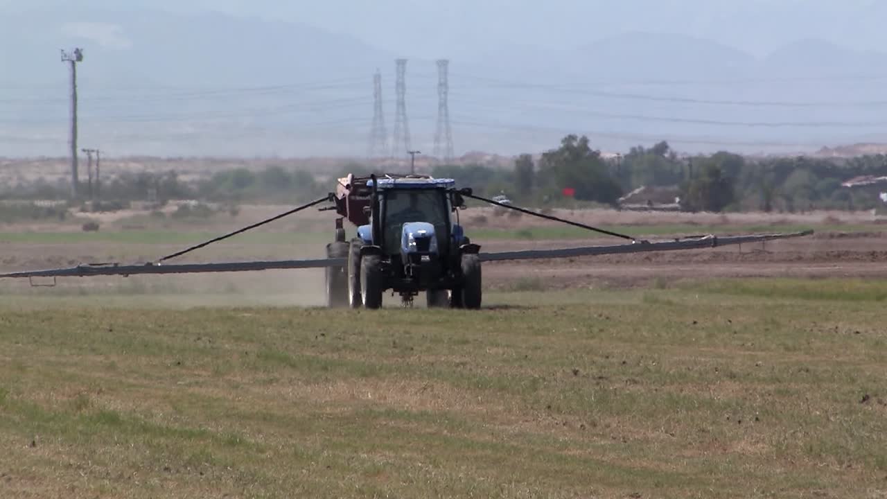 tractor fertilizando campo de alfalfa en california, ee.uu.