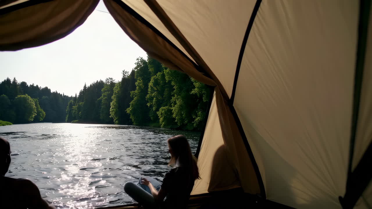 View from inside a tent or boat looking out onto a scenic river with people