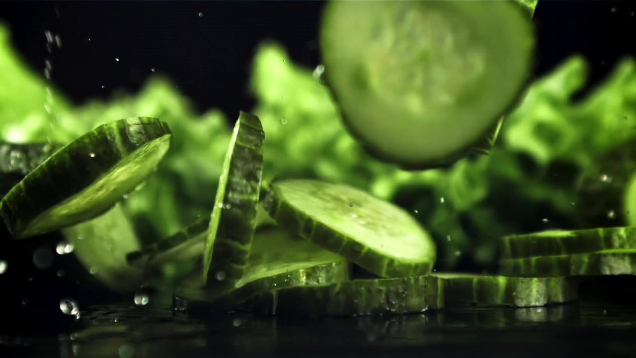 Green Cucumber Slices Falling in Slow Motion with Water Drops