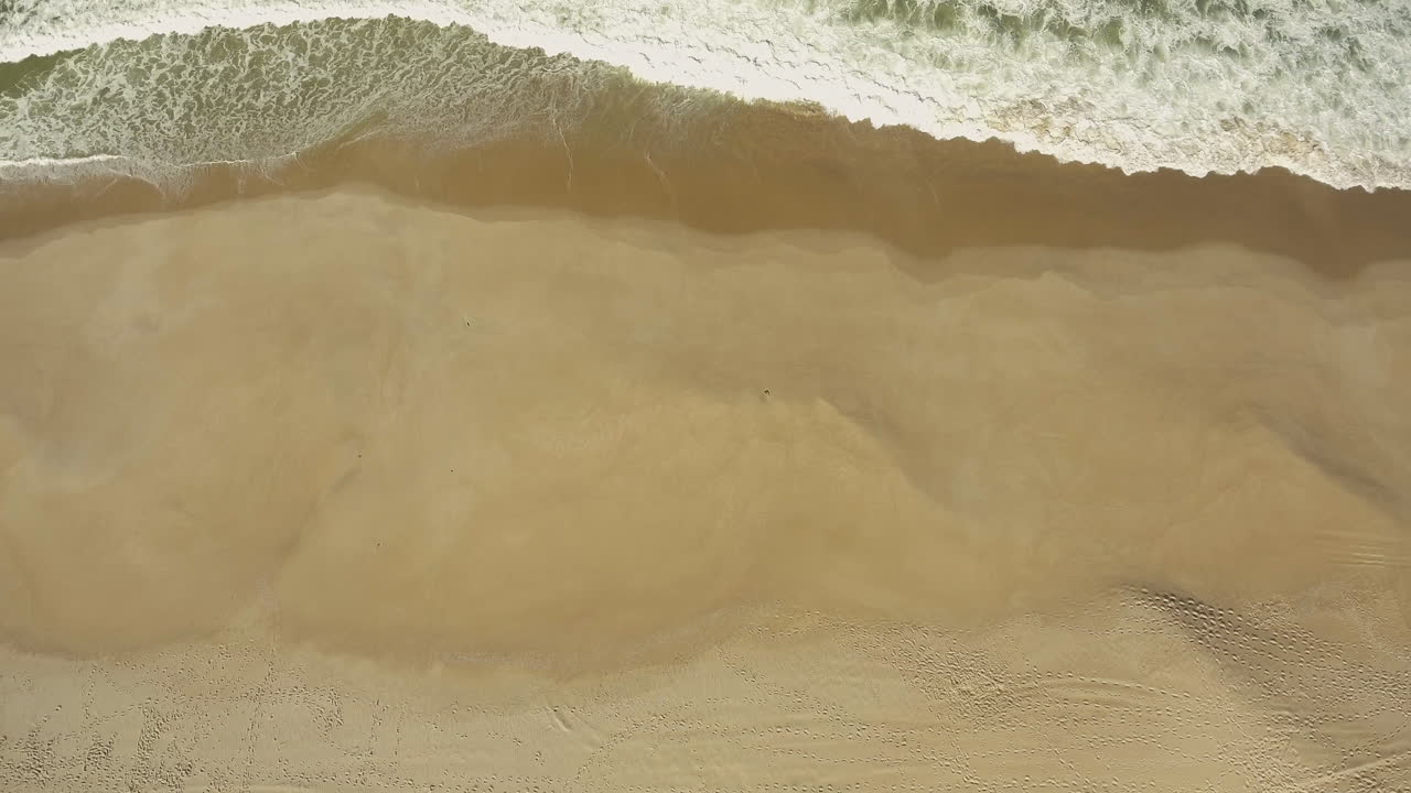 포루투갈의 캠핑 프라이아 다 게일 근처 강풍의 모래사장에서 거품이 이는 파도 - 공중 드론 샷