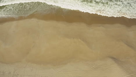 foamy waves splashing on the sandy coast of gale, near camping praia da gale in portugal - aerial drone shot