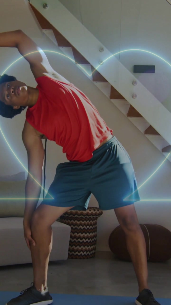 Vertical video: Man raising arm doing side stretch in home, neon heart tracing torso for fitness