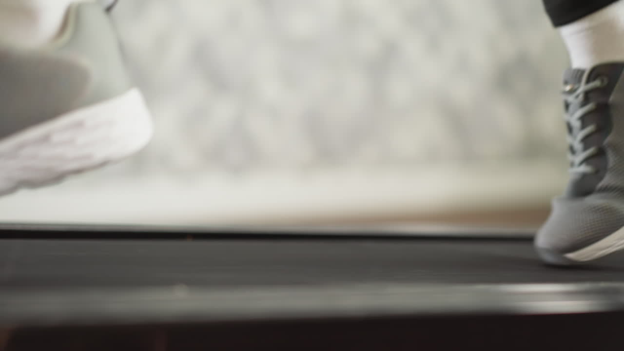 가정용 트레드밀 클로즈업에서 달리는 여성 발. 스포츠 스니커를 입은 스포츠 여자가 가정 훈련 장비에서 조 루틴을 느린 동작으로합니다.