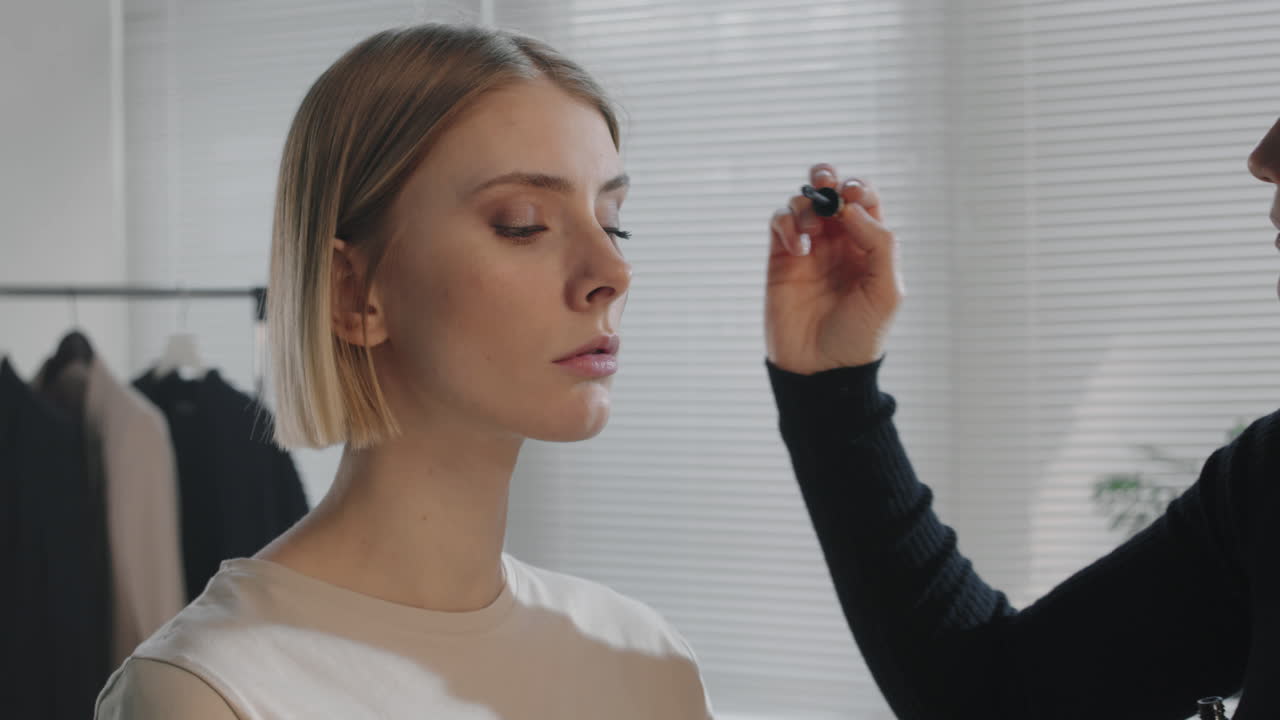 artista de maquillaje femenina poniendo máscara en el modelo