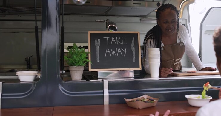 Donna afroamericana che serve cibo da asporto da un food truck