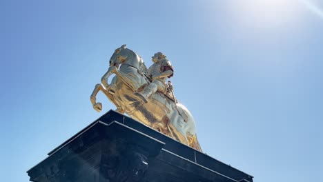 golden equestrian statue against a bright blue sky