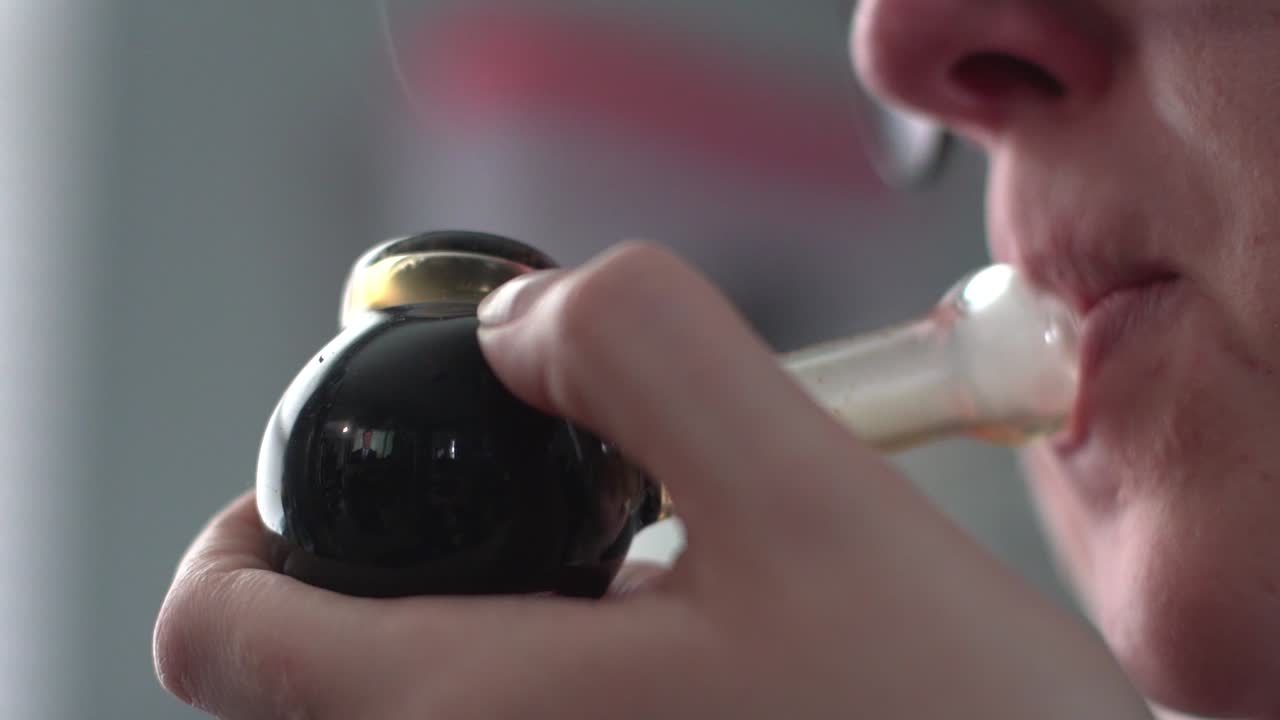 흐릿한 배경에 격리된 연기 파이프를 손에 들고 있는 여성 - 극단적인 근접 촬영