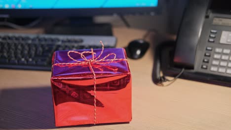 a man holds a gift on his office desk at christmas and new year eve. surprises and gifts for the holidays