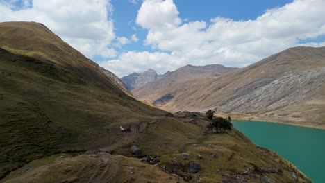 ancient inca ruins in a remote mountain valley, revealing a beautiful turquoise lake on the huayhuash trek in peru - aerial flyover