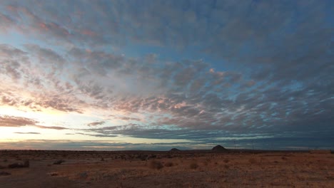 Time-lapse,-golden-sunlight-washes-over-sunrise-Mojave-Desert-with-cloudy-sky